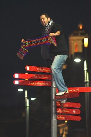 Un jove celebrant el campionat de Lliga damunt un cartell indicador
