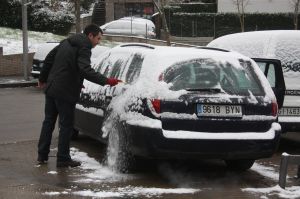 Un veí de Girona retirant la neu dels vidres del seu cotxe