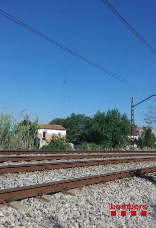 Una grua frega la catenària del tren a Figueres provocant un incendi de canyes