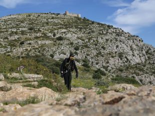 Un home vestit de submarinista pujant el Montgrí encurioseix la xarxa