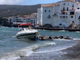 Embarrancada una barca en unes roques davant la platja de Cadaqués