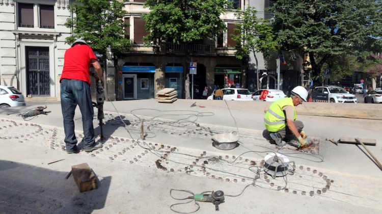 Dos operaris traient les lletres de 'Plaça Constitució' que formaven els brolladors. ACN