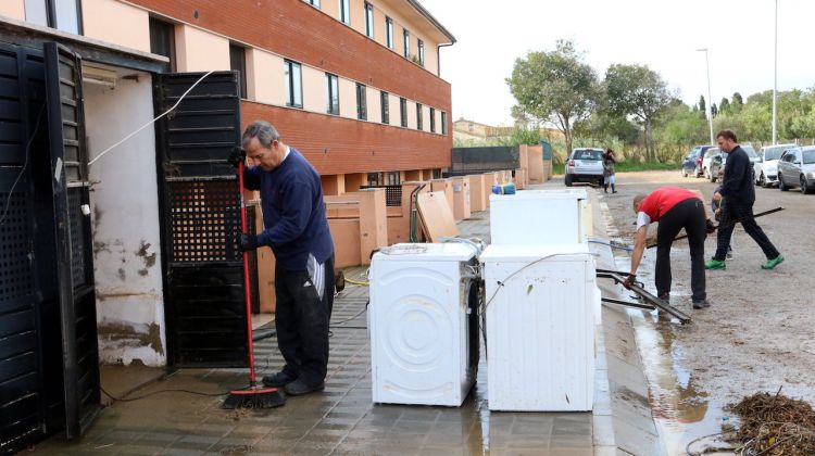 Alguns veïns netejant les seves cases a Vilatenim amb diversos electrodomèstics afectats. ACN