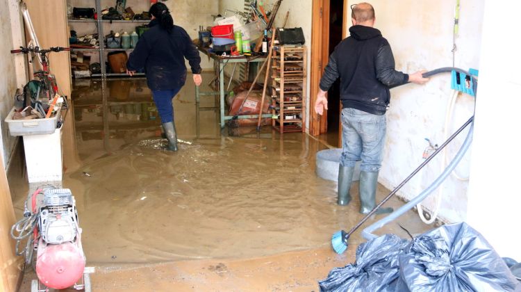 Dos veïns netejant el garatge de casa seva a Vilatenim. ACN