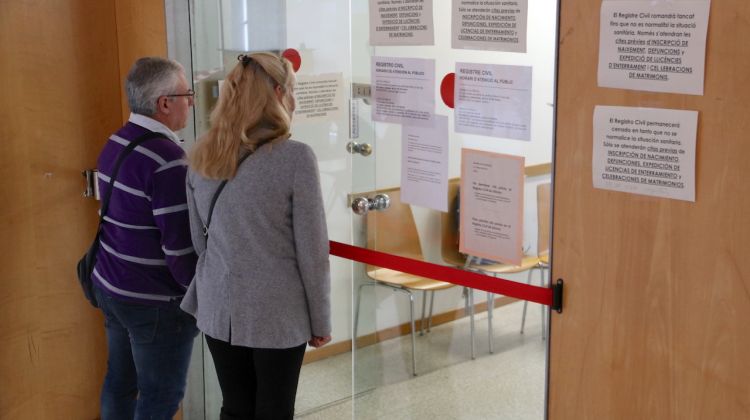 Una parella davant de la porta del Registre Civil dels Jutjats de Girona tancada al públic pel coronavirus. ACN