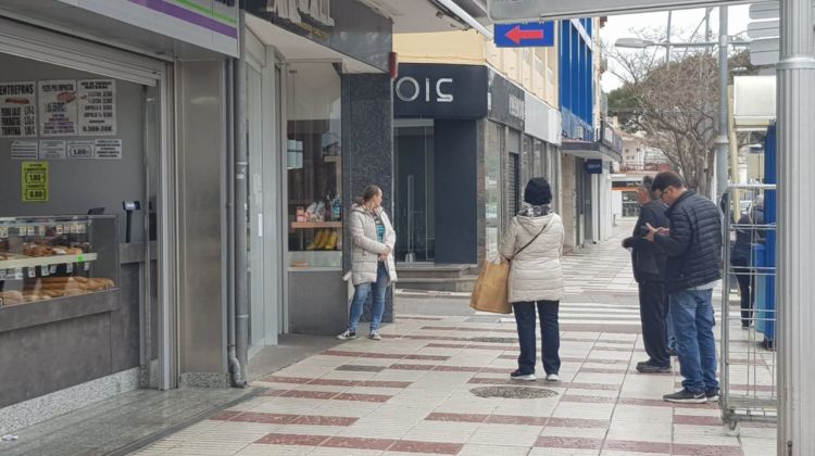 Algunes persones fent cua per entrar en un establiment de Platja d'Aro per comprar aliments. ACN