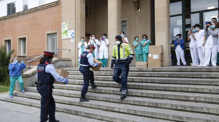 Agents dels Mossos d'Esquadra portant material sanitari als treballadors del Trueta que diversos ciutadans han donat mentre el personal aplaudeix. ACN