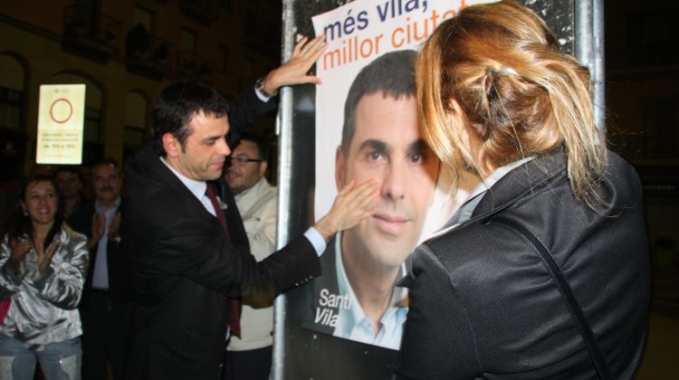 El candidat de CiU, Santi Vila, durant la penjada de cartells a la plaça Ernest Vila © ACN