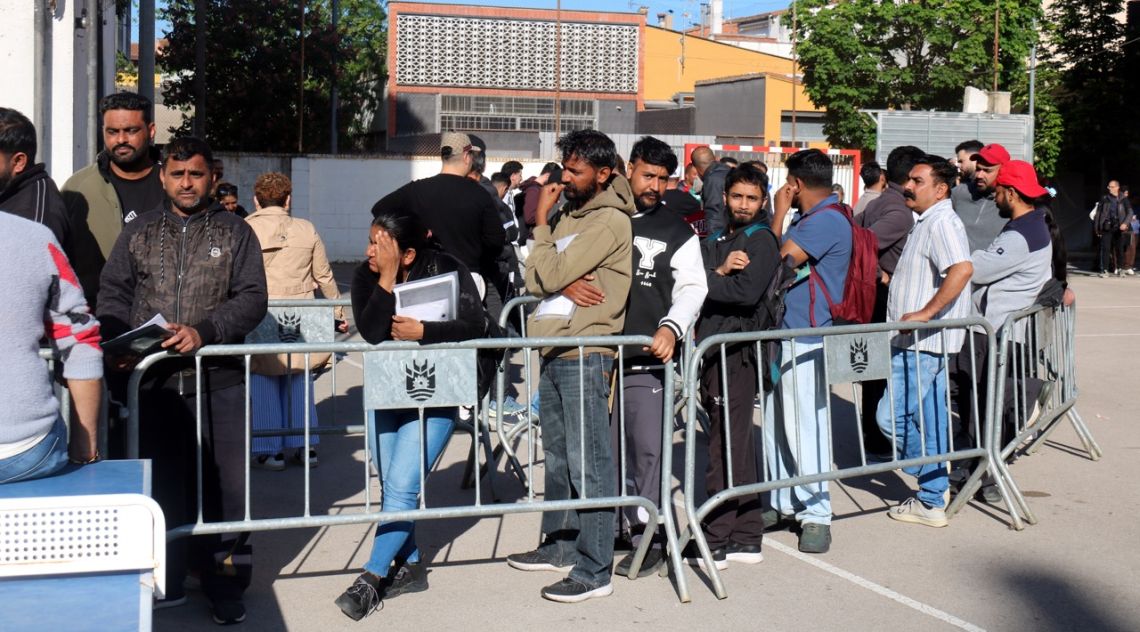 Cues de migrants a Salt per informar-se del procés de regularització extraordinària