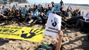 Activistes i nedadors, vestit de negre, s'han estès a la sorra de la platja de Blanes © ACN