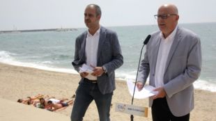 Un grup de banyistes observa des de la sorra la roda de premsa de Miquel Buch i Lluis Corominas © ACN