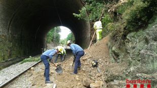 Els bombers ajudant en la neteja de la via