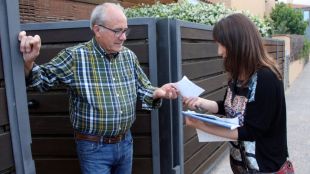 Un veí del carrer Alfons XII de Palafrugell lliura el sobre a l'enquestadora © ACN