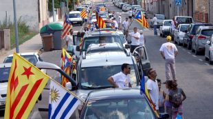 Una filera de cotxes engalanats amb senyeres i estelades a la C-66 creuant Flaçà © ACN