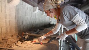 Una restauradora treballant a la part més alta de la portalada de Ripoll © ACN