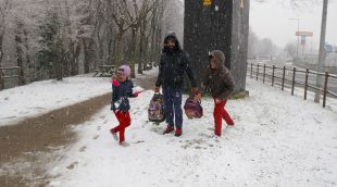 Dos nens i un pare jugant amb la neu a Olot aquesta tarda