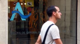 Un jove passa per davant del logotip que hi ha a la porta de la seu d'AGISSA