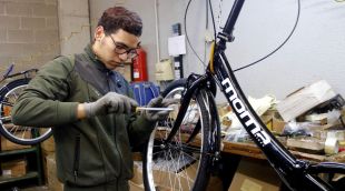En Youssef, que va seguir un programa de Càritas, muntant una bicicleta a la feina