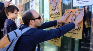 Un home enganxa un cartell per l'alliberament dels presos a la plaça Universitat de Barcelona