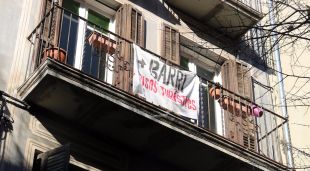 Un balcó de la Rambla on hi llueix una pancarta que reclama menys habitatges d'ús turístic al Barri Vell de Girona