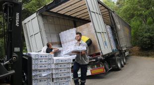 Uns homes retirant la càrrega manualment del camió bolcat a Riudarenes