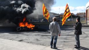 Dos treballadors de la planta de Torraspapel de Sant Joan les Fonts (Garrotxa) mirant-se els pneumàtics encesos © ACN