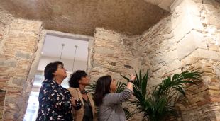 L'arqueòloga i les dues propietàries de l'òptica, mirant el pany de muralla medieval