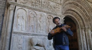 El musicòleg Antoni Madueño tocant un instrument medieval davant la Portalada de Ripoll