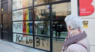 El centre LGTBI de l'Ajuntament de Barcelona, ple de pintades feixistes, mentre una veïna ho observa