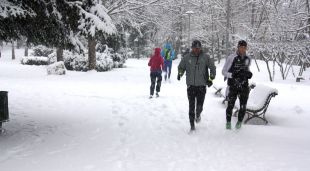 Diverses persones corrent per l'entorn de l'estany de Puigcerdà, cobert de blanc per la nevada