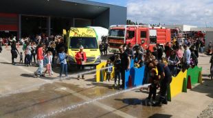El parc de Bombers de Figueres ple de gent i dos nens fent anar la manguera d'aigua