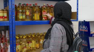 Una usuària del Centre de Distribució d'Aliments de Salt agafant una ampolla d'oli