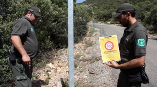 Dos Agents Rurals a punt de col·locar un cartell que indica que està prohibit accedir a la serra del Montsec
