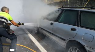 El mosso apagant les flames al vehicle incenciat a la C-65