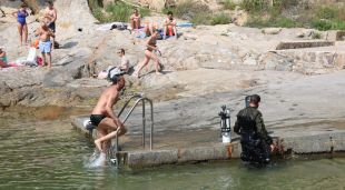 Un submarinista amb un banyista compartint la zona i al fons més persones prenent el sol