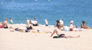 Diversos turistes estirats a la platja prenent el sol a Lloret