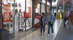 Alguns compradors del centre comercial Espai Gironès passant per davant d'una botiga que ofereix descomptes durant les rebaixes