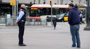 Un Mosso pregunta el destí i motiu del viatge a un vianant a la plaça Catalunya de Barcelona durant el confinament
