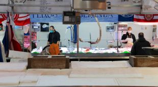 En primer pla, una peixateria del Mercat del Lleó de Girona tancada i, al fons, dues atenent clients