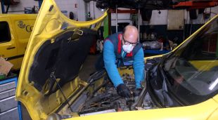 Un mecànic reparant una furgoneta de Correus a l'interior del taller Reparacions Panella de Riudellots de la Selva