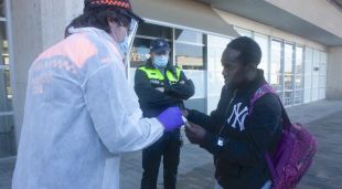 Un usuari del transport públic rebent una mascareta per part d'un voluntari