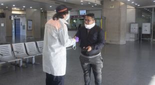 Un voluntari entregant una mascareta a l'estació de tren convencional, aquest matí
