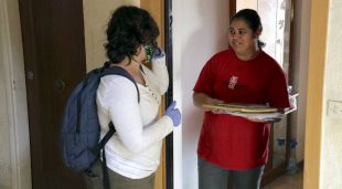 Una tècnica de Càritas Salt entregant material escolar a una família