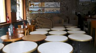 Taules i cadires de la terrassa amuntegades dins un local tancat de la plaça Independència de Girona