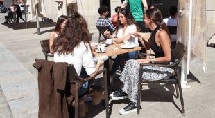 Quatre amigues fent un cafè en una terrassa de la plaça de la Independència de Girona
