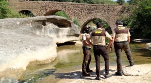 Tres guardes rurals privats, i al fons la riera