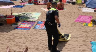Un policia local retirant una de les tovalloles de la platja de Tamariu