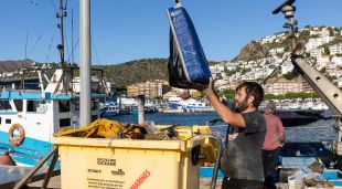 Un pescador buidant alguns dels residus que s'han trobat a alta mar en el Port de Roses