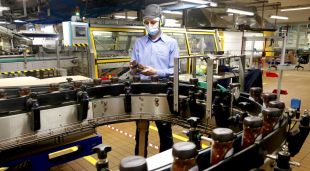 Un treballador inspecciona un pot de Nescafé al costat d'una de les línies de producció de la fàbrica de Girona