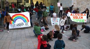 Diversos nens dibuixant mascaretes al terra amb una creu a sobre mentre els pares demanen a Educació que no obligui als alumnes a portar-ne a l'aula